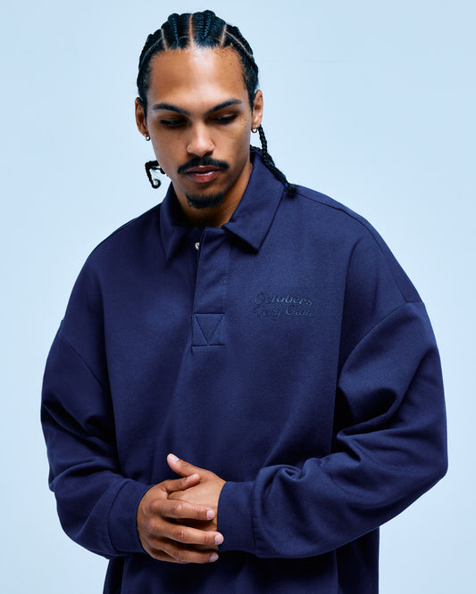 Navy blue rugby polo with embroidered script text on chest and collared neckline.