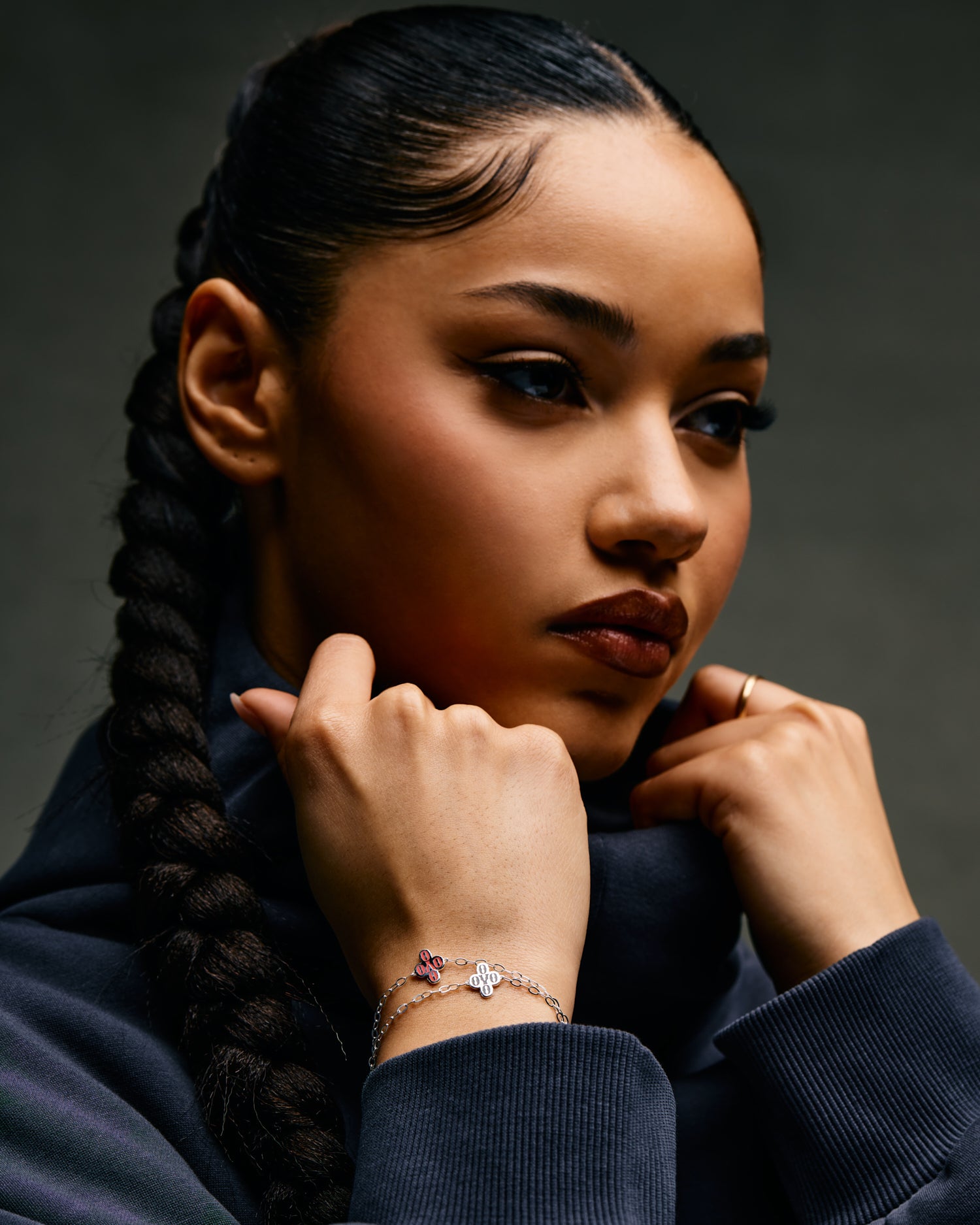 Woman with braided hair wearing a dark blue October's Very Own sweater against a gray background