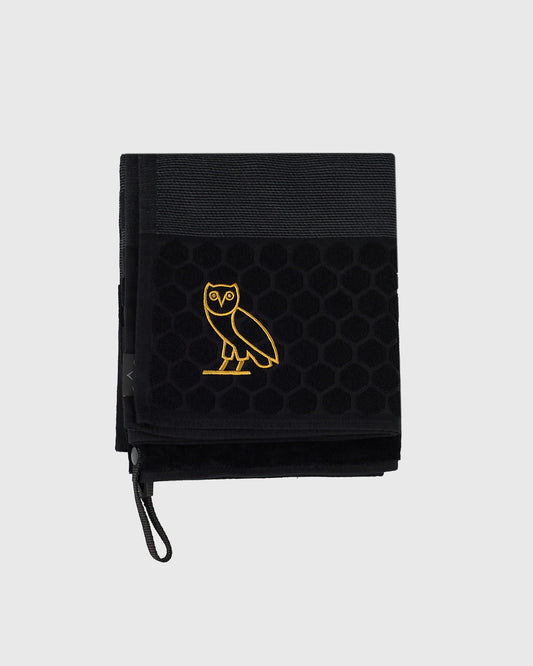 Black golf towel with gold embroidered owl logo and hanging loop.