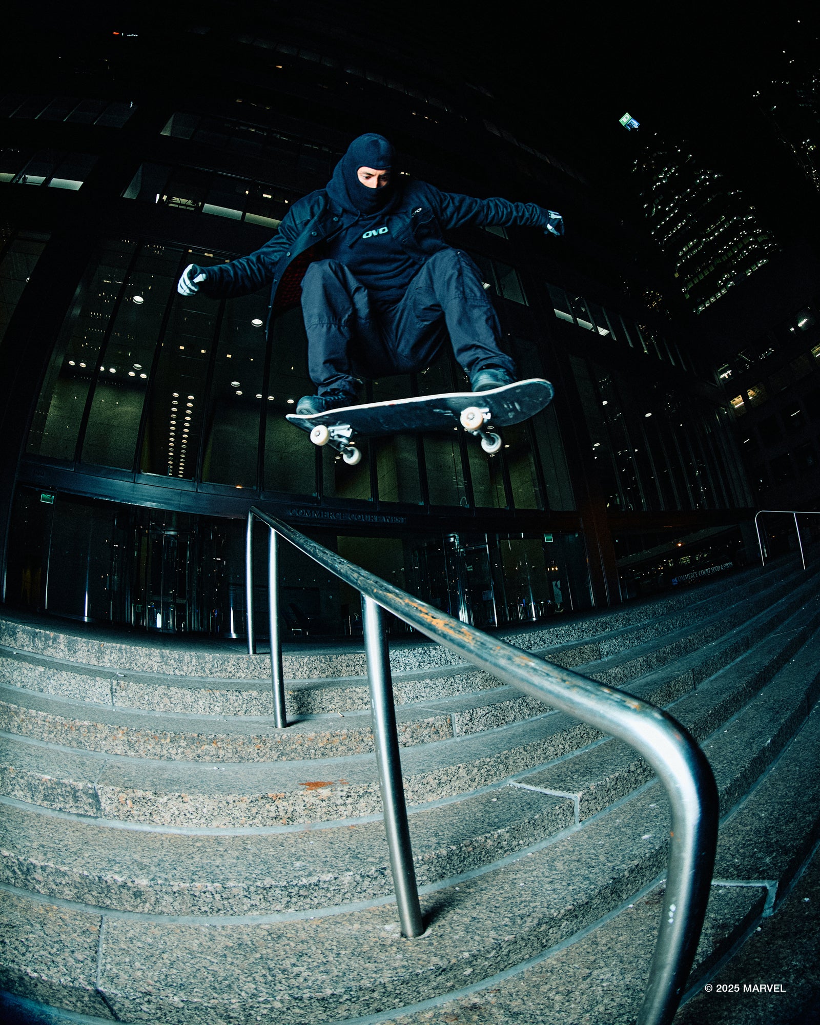 Skateboarder performing a trick on a railing at night.
