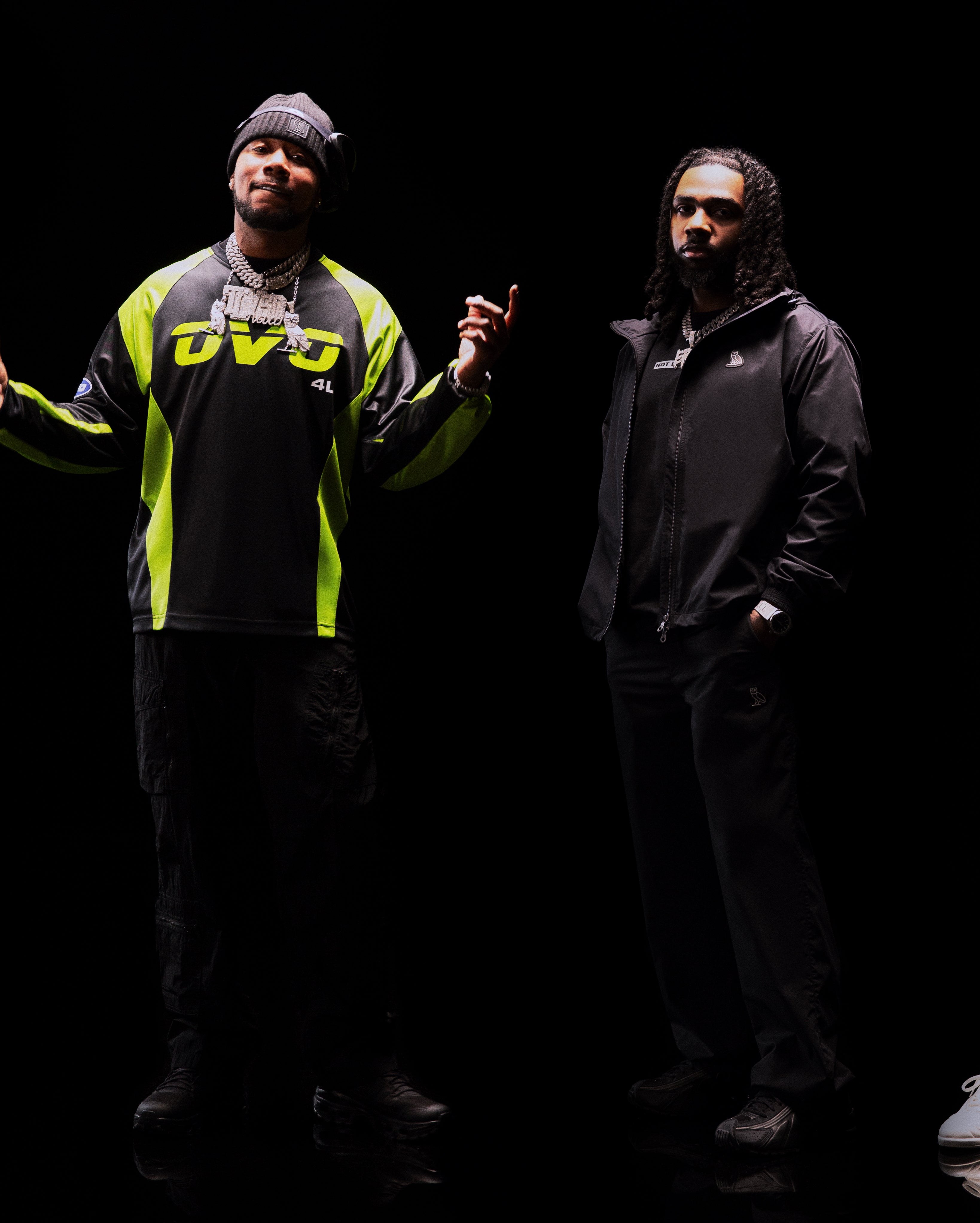 Translation missing: fr.Two individuals wearing jackets with visible branding against a dark background
