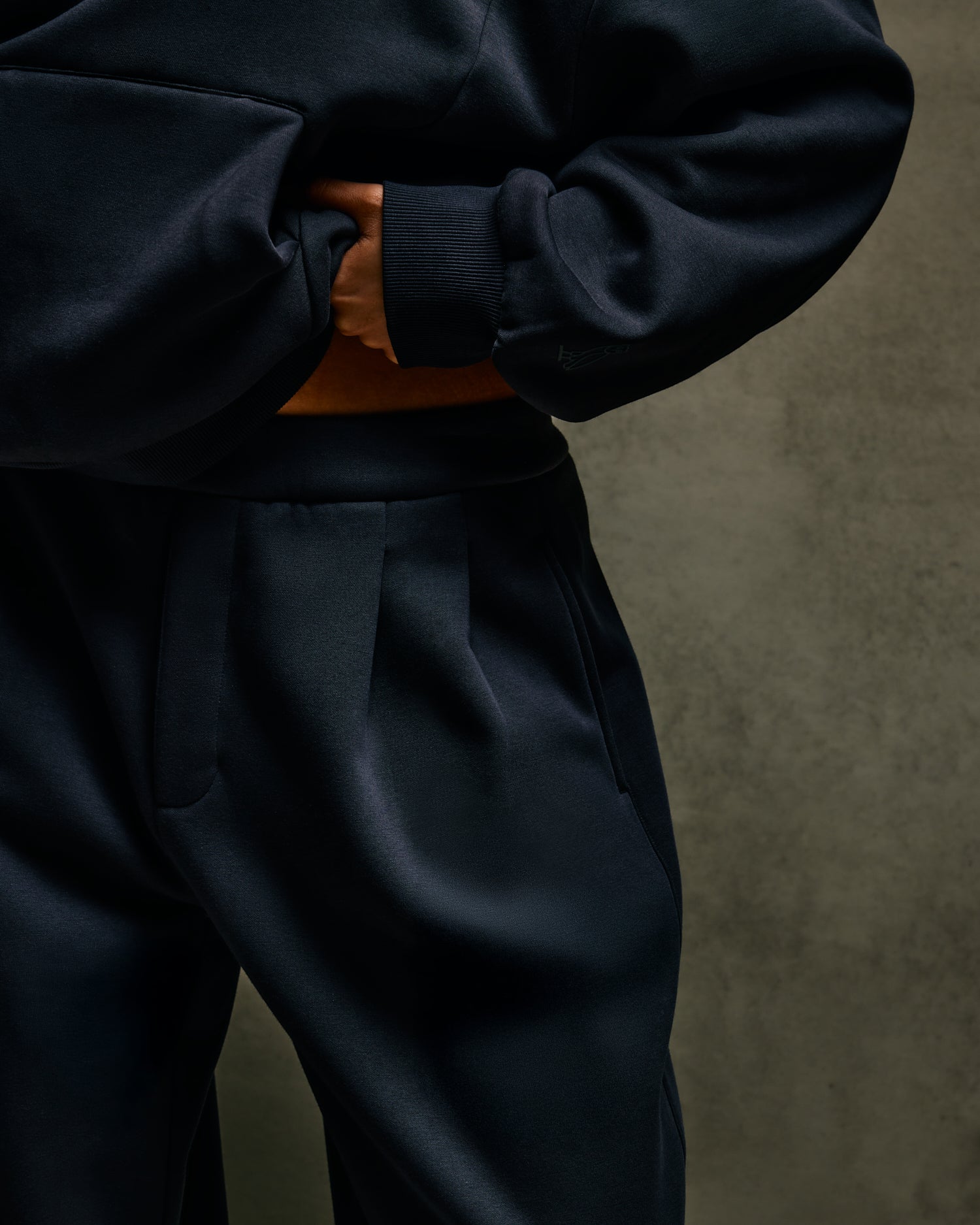 Person wearing a dark blue October's Very Own tracksuit against a brown background