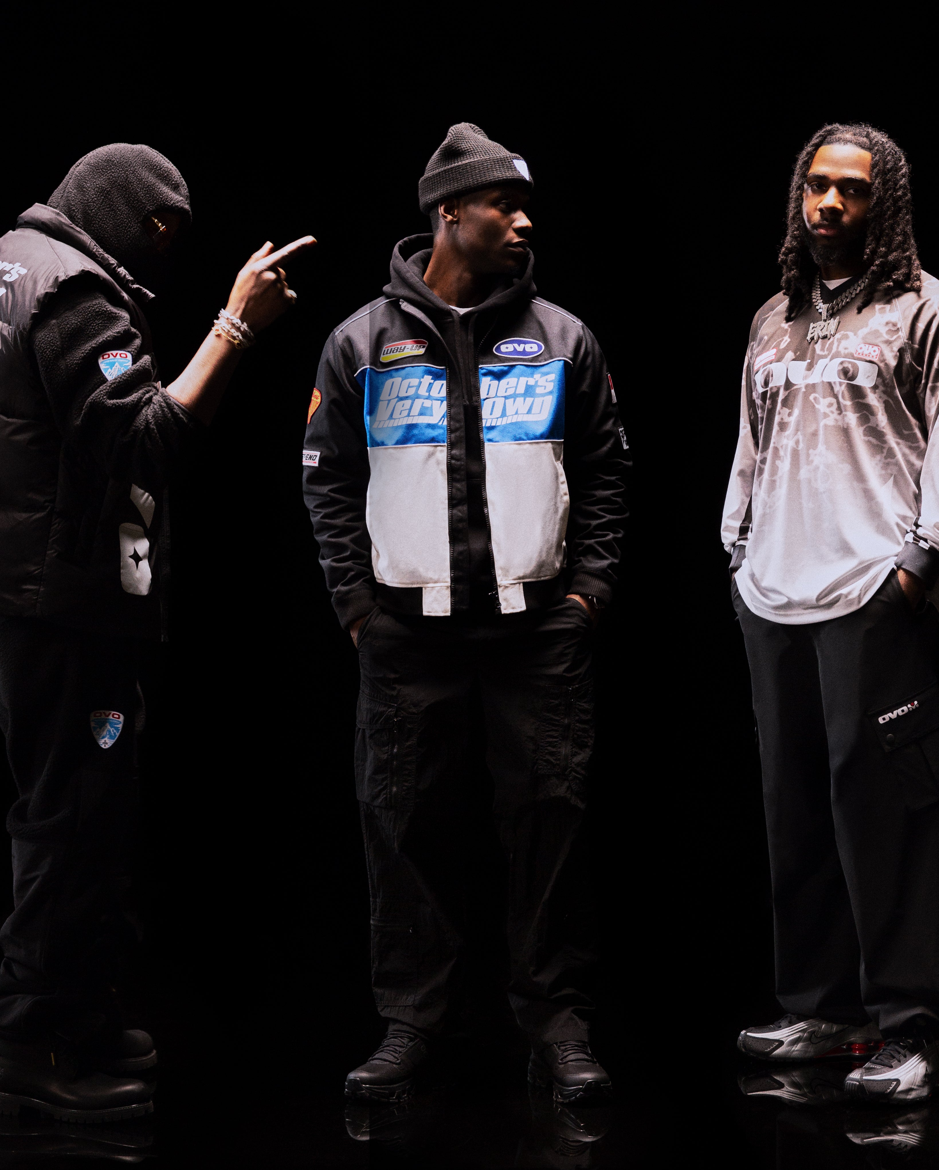 Translation missing: fr.Three individuals wearing branded jackets against a black background