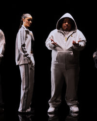 Translation missing: fr.Two people wearing matching gray tracksuits on a black background