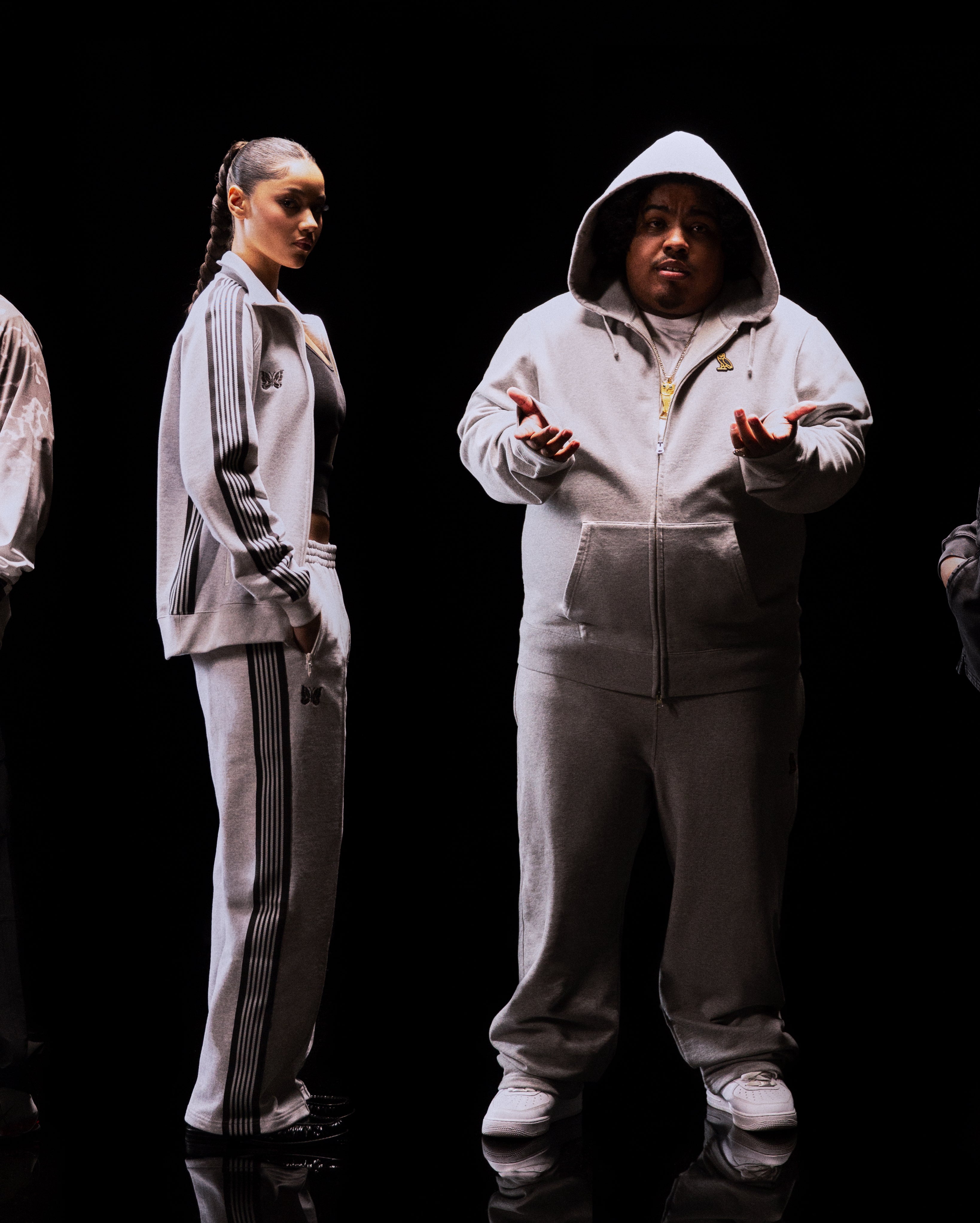Translation missing: fr.Two people wearing matching gray tracksuits on a black background
