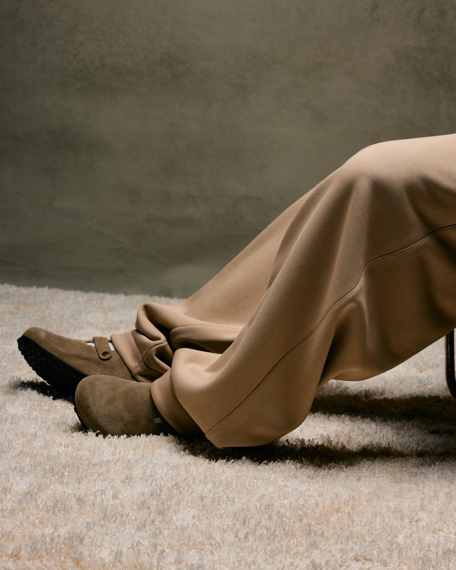 Person wearing beige October's Very Own pants and shoes on a textured surface with a neutral background