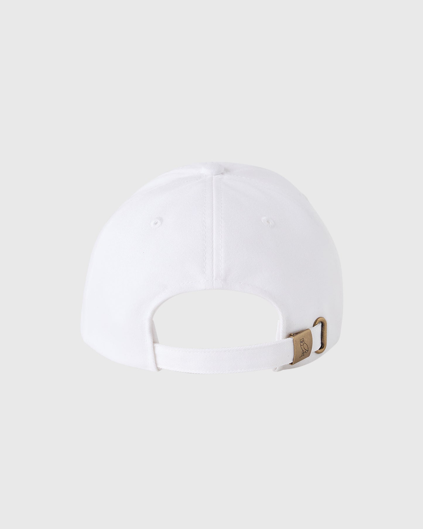 White baseball cap with pom pom on crown and adjustable strap with brown buckle closure at back.