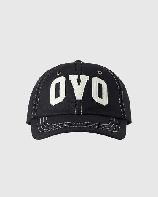Black wool cap with white "OVO" embroidered on front, contrast stitching, and brass eyelets.