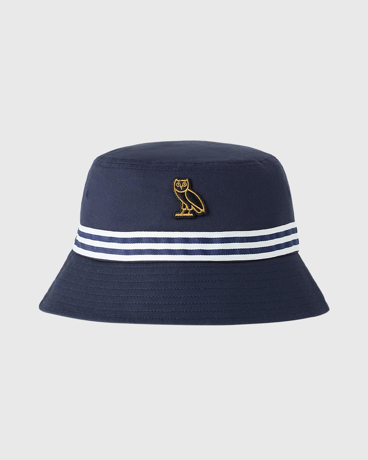 Navy bucket hat with gold owl embroidery on crown and navy-white striped band around base.