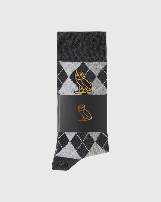 Black sock with argyle pattern in white and gray, featuring a gold owl logo on the calf area.