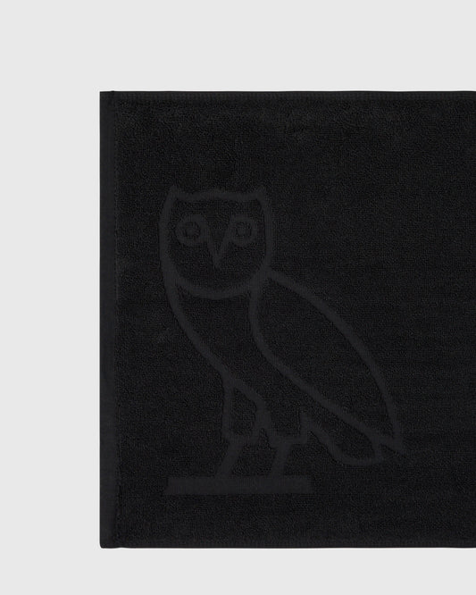 Black golf towel with embossed owl logo in center.