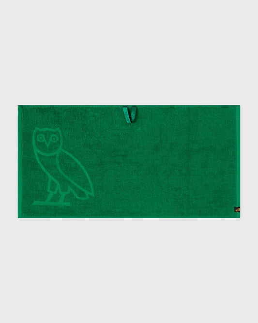 Green golf towel with owl logo embossed on left side and hanging loop at top.