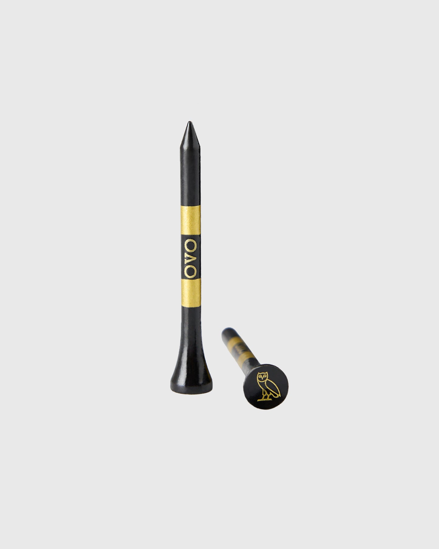 Black golf tees with gold band and OVO logo, shown in standard and ball marker styles.