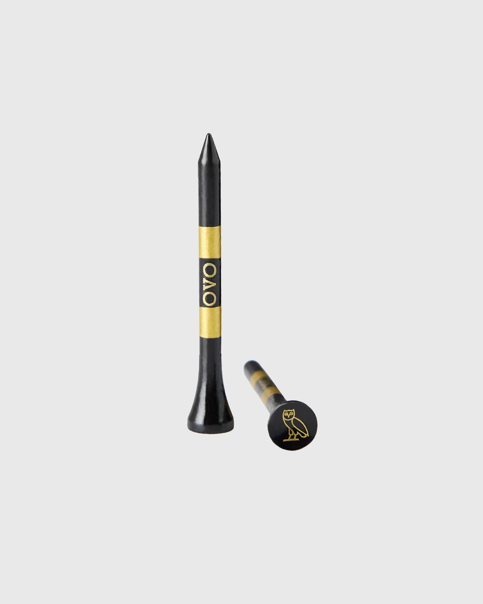Black golf tees with gold band and OVO logo, shown in standard and ball marker styles.