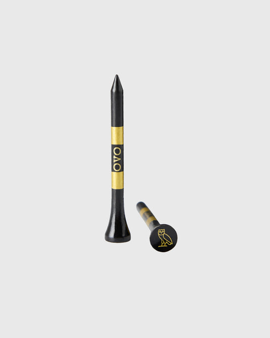 Black golf tees with gold band and OVO logo, shown in standard and ball marker styles.
