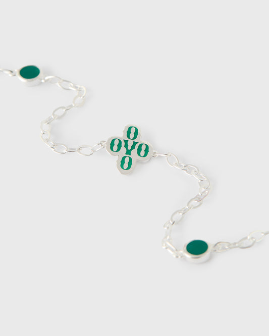 Silver chain bracelet with teal pom pom charms and oval teal stone accents.