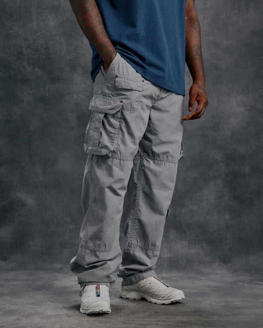 Grey cargo pants with multiple pockets on thighs, worn with blue shirt.