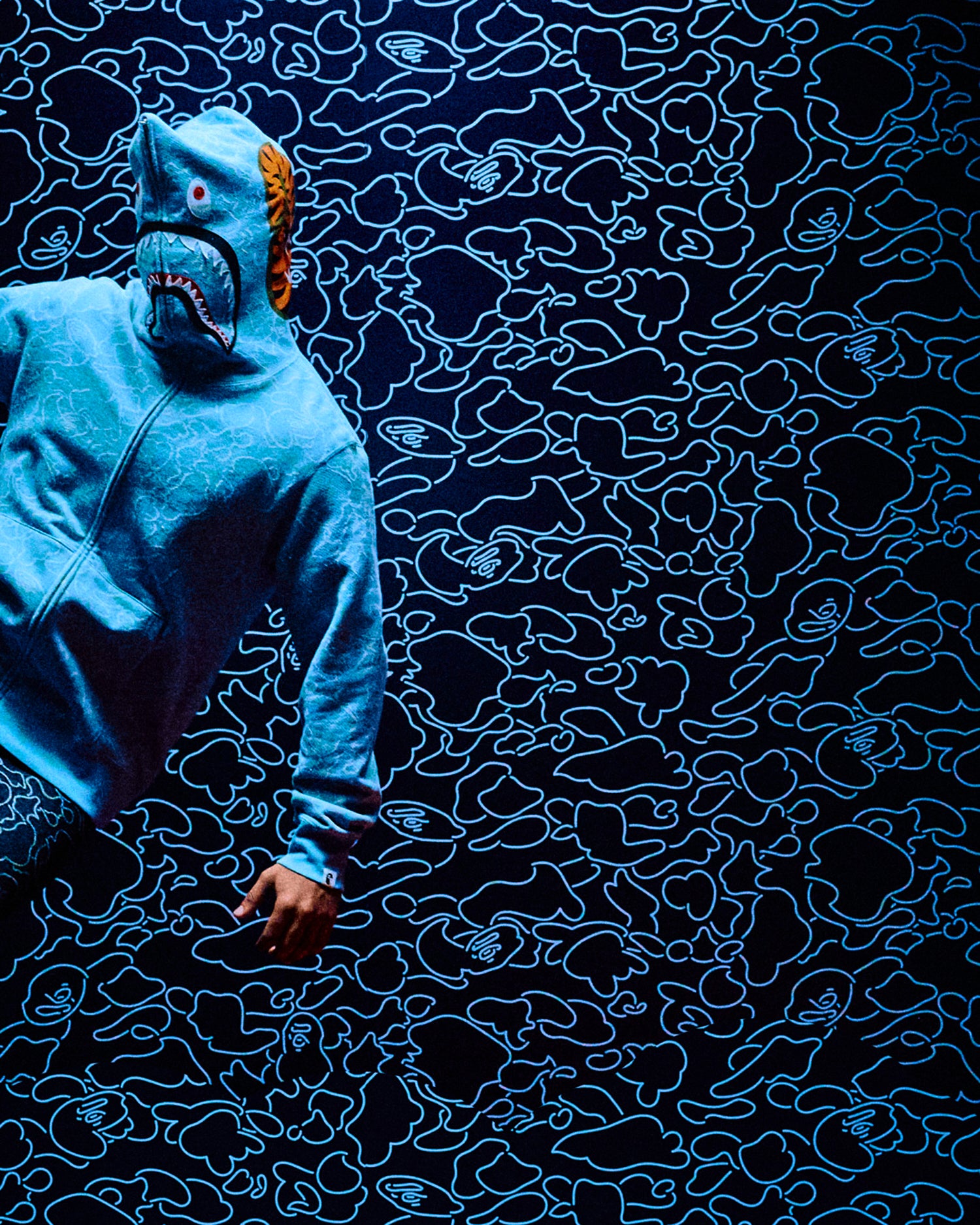 Person wearing a blue patterned Octobers Very Own x Bape outfit interacting with a dark textured surface
