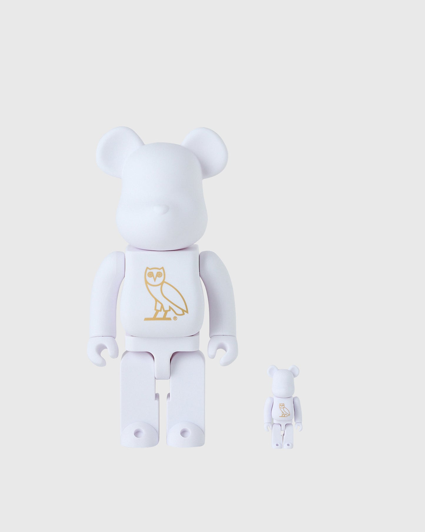 Pearl white BE@RBRICK collectible figures in large and small sizes with gold owl design on chest.