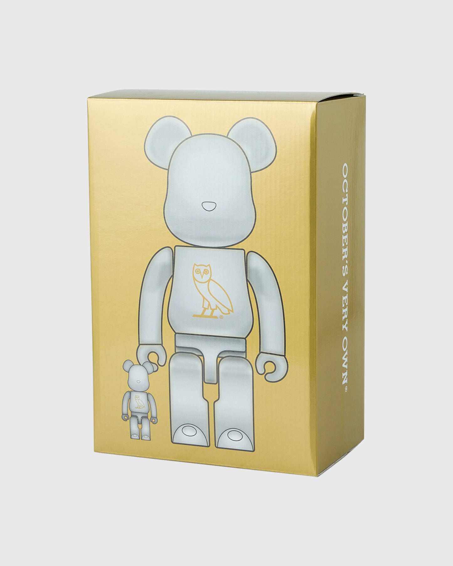 Pearl white BE@RBRICK figures in two sizes with owl chest design displayed in gold packaging box.