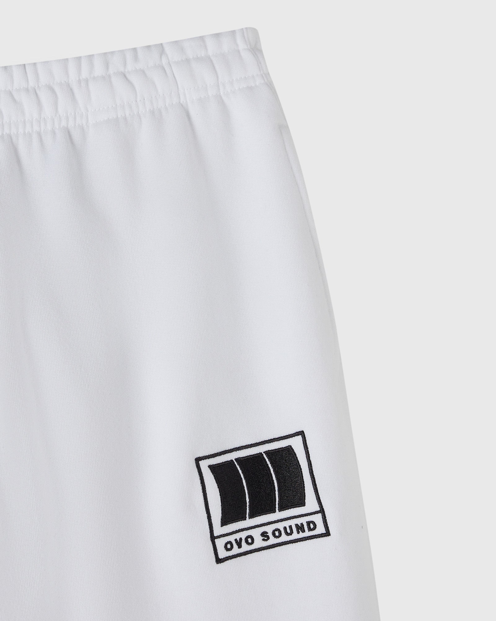 White sweatpant with elastic waistband and black OVO Sound logo patch on thigh.