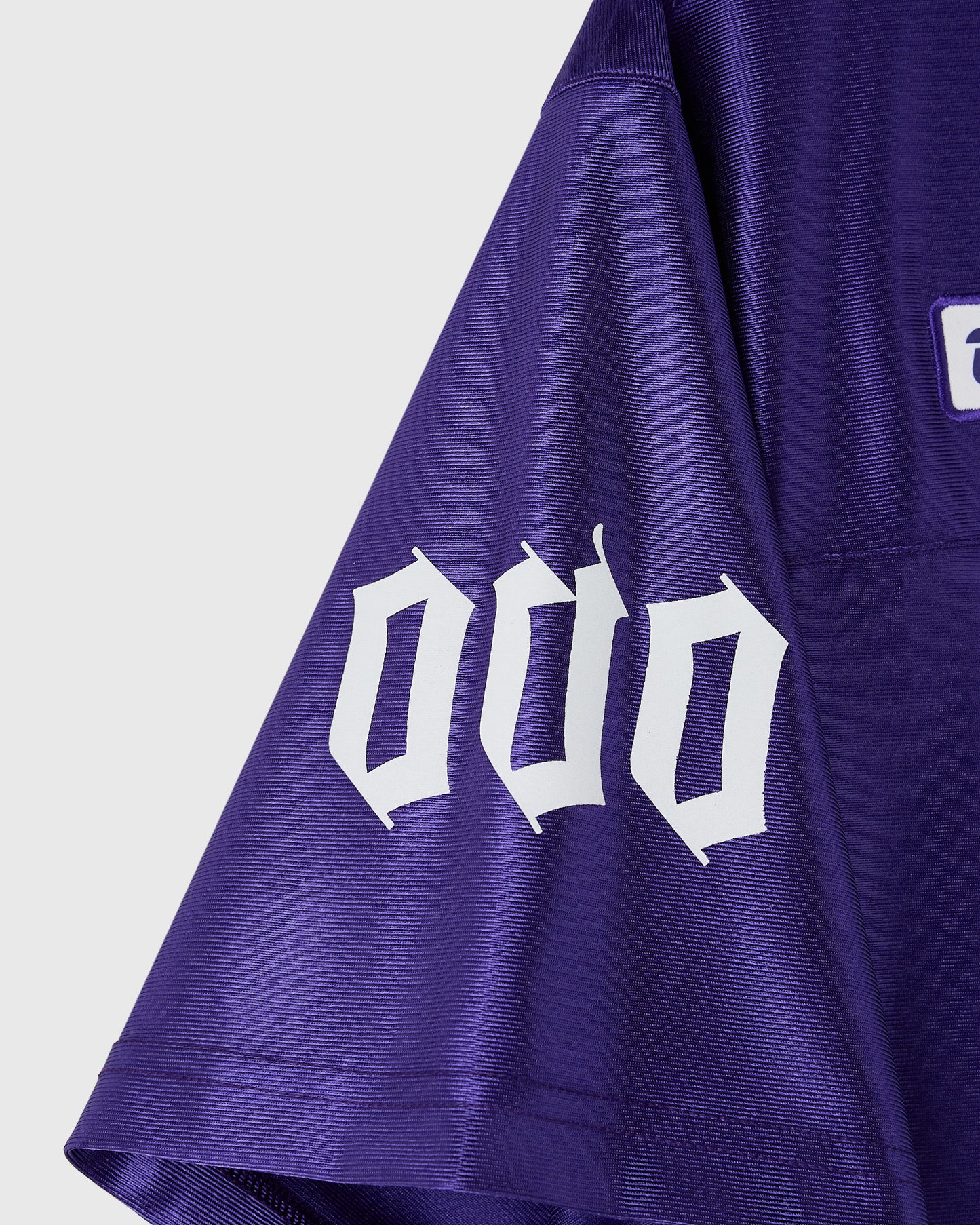 Violet football jersey with white gothic-style number and ribbed texture fabric.