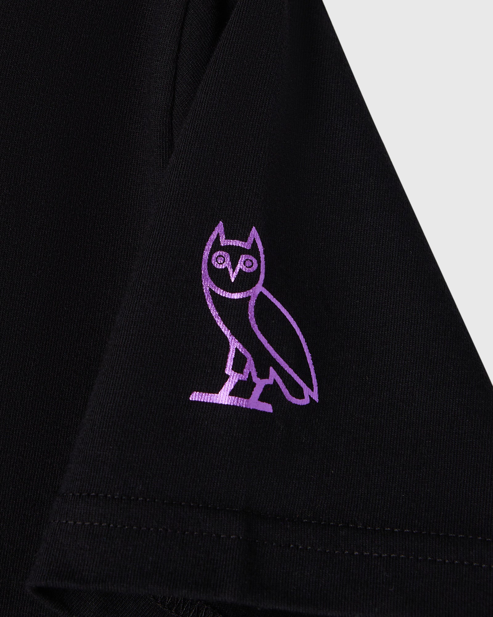 Black t-shirt with purple embroidered owl graphic on chest.