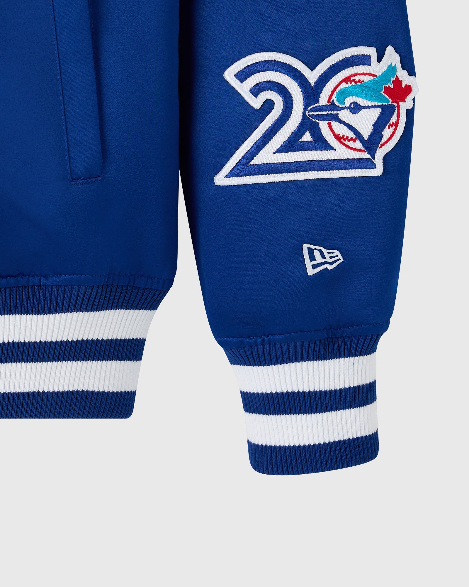 Blue varsity jacket with Toronto Blue Jays logo, white and blue striped ribbed cuffs, and New Era branding.