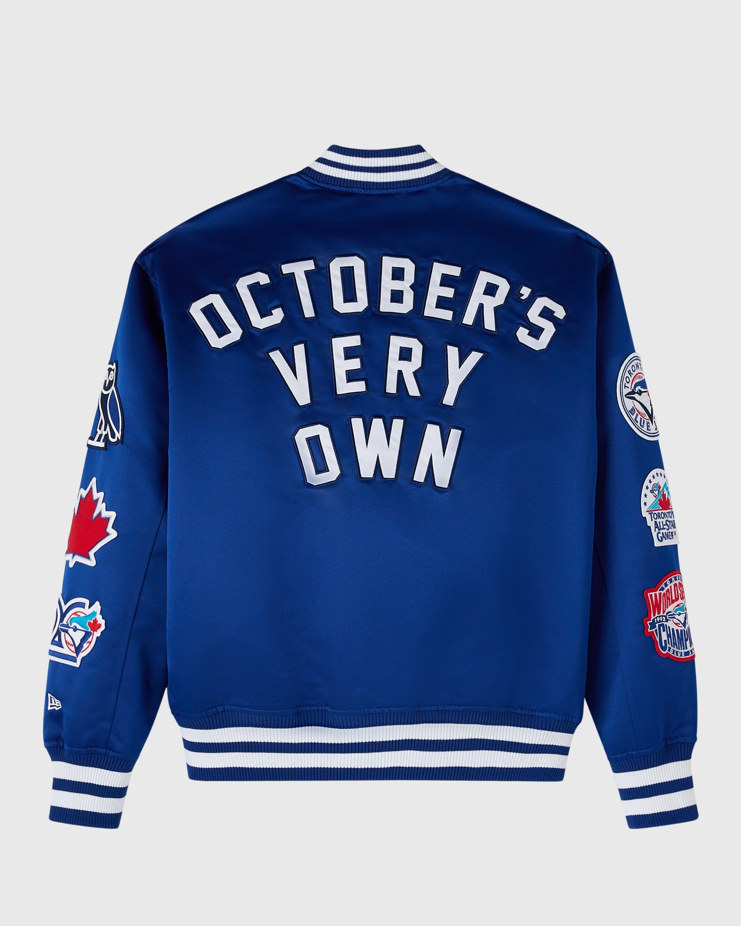 Blue varsity jacket with white "October's Very Own" text, striped collar and cuffs, and team logos on sleeves.