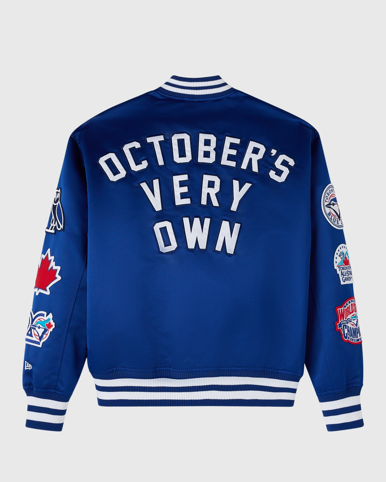 Blue varsity jacket with white "October's Very Own" text, striped collar and cuffs, and team logos on sleeves.