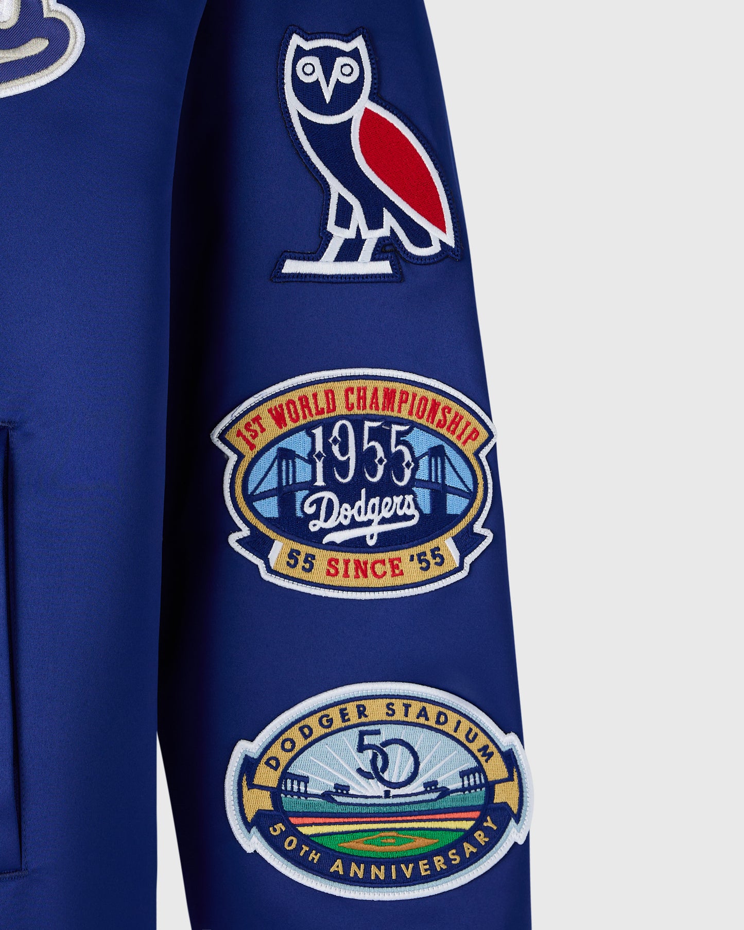 Blue varsity jacket with white owl logo, 1955 World Championship patch, and 50th anniversary Dodger Stadium patch on sleeve.