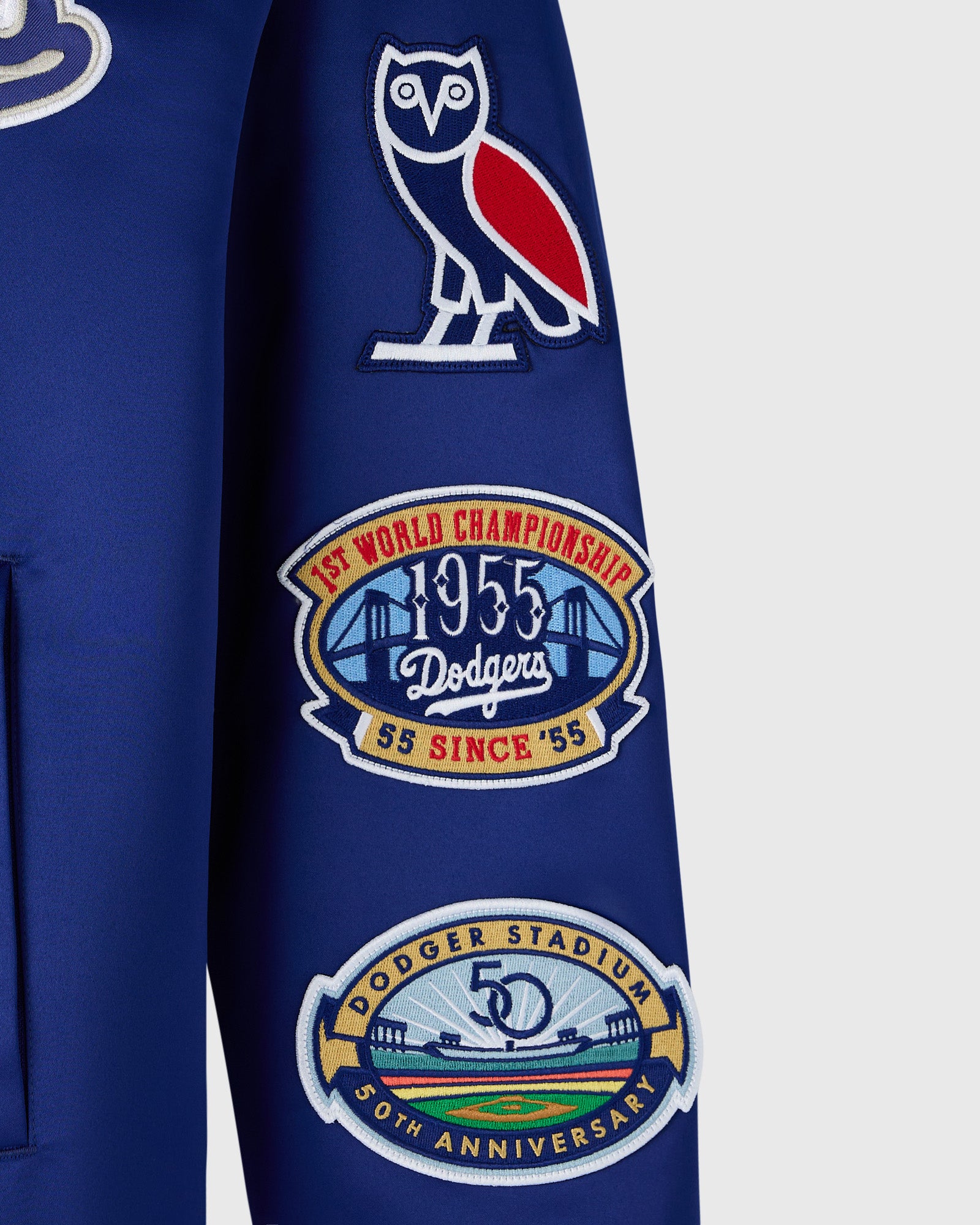 Blue varsity jacket with white owl logo, 1955 World Championship patch, and 50th anniversary Dodger Stadium patch on sleeve.