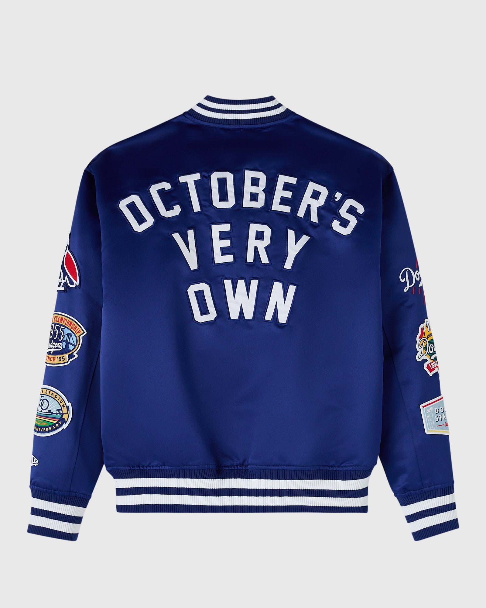 Blue varsity jacket with white "October's Very Own" text on back, striped ribbed collar and cuffs, and embroidered patches on