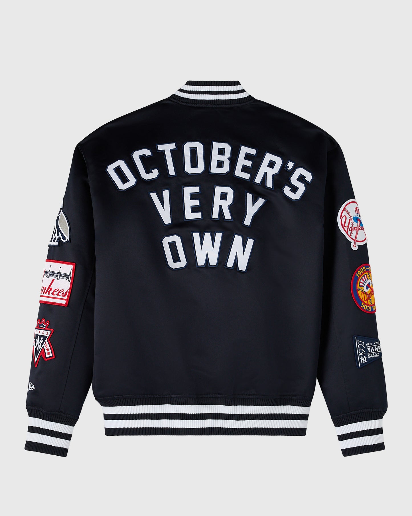 Navy varsity jacket with white "October's Very Own" text on back, striped ribbed collar and cuffs, and Yankees patches on sle