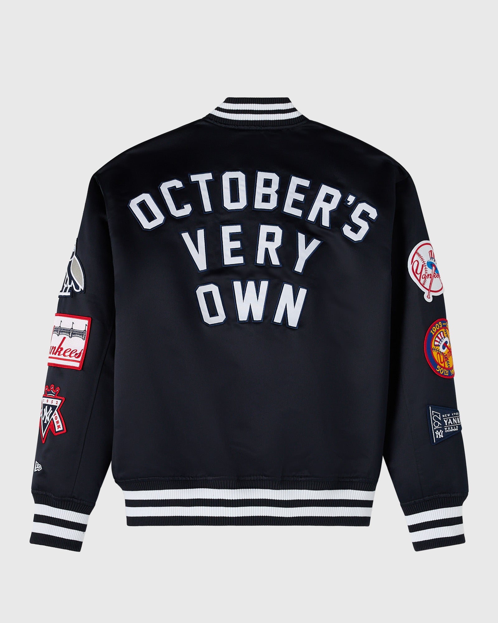 Navy varsity jacket with white "October's Very Own" text on back, striped ribbed collar and cuffs, and Yankees patches on sle