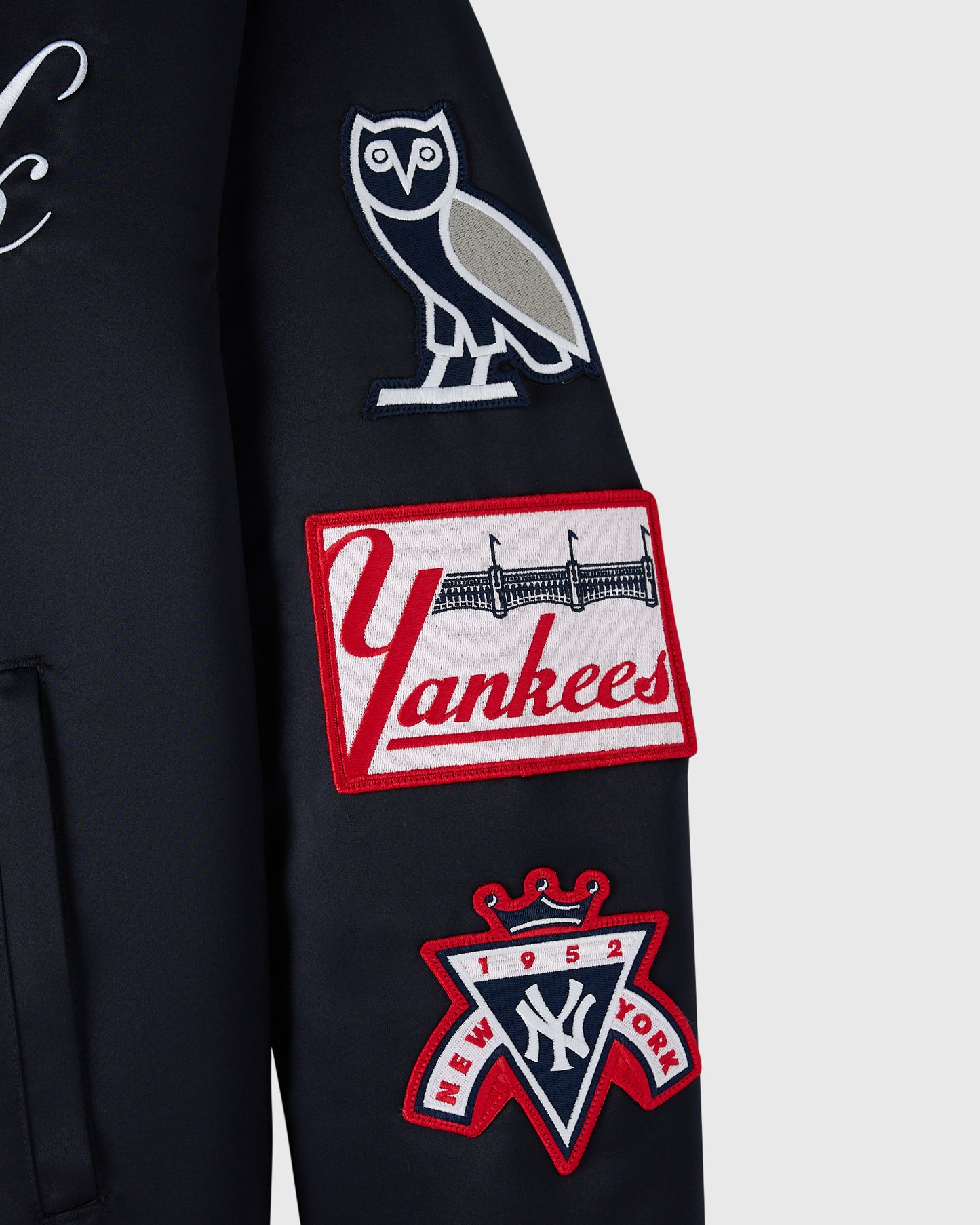 Navy varsity jacket with embroidered owl, Yankees logo, and 1952 crown patch on sleeve.