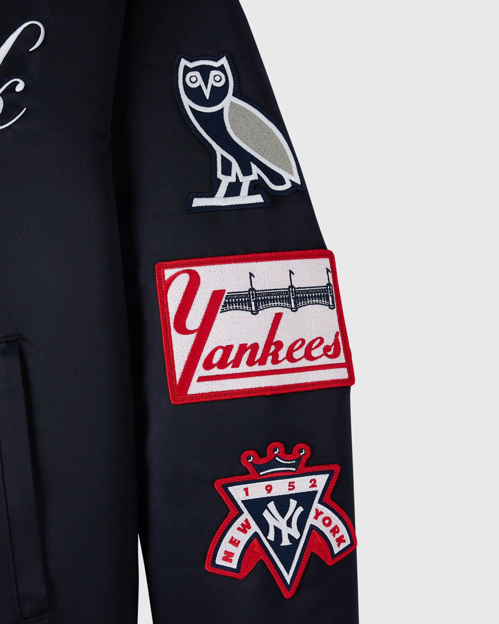 Navy varsity jacket with embroidered owl, Yankees logo, and 1952 crown patch on sleeve.