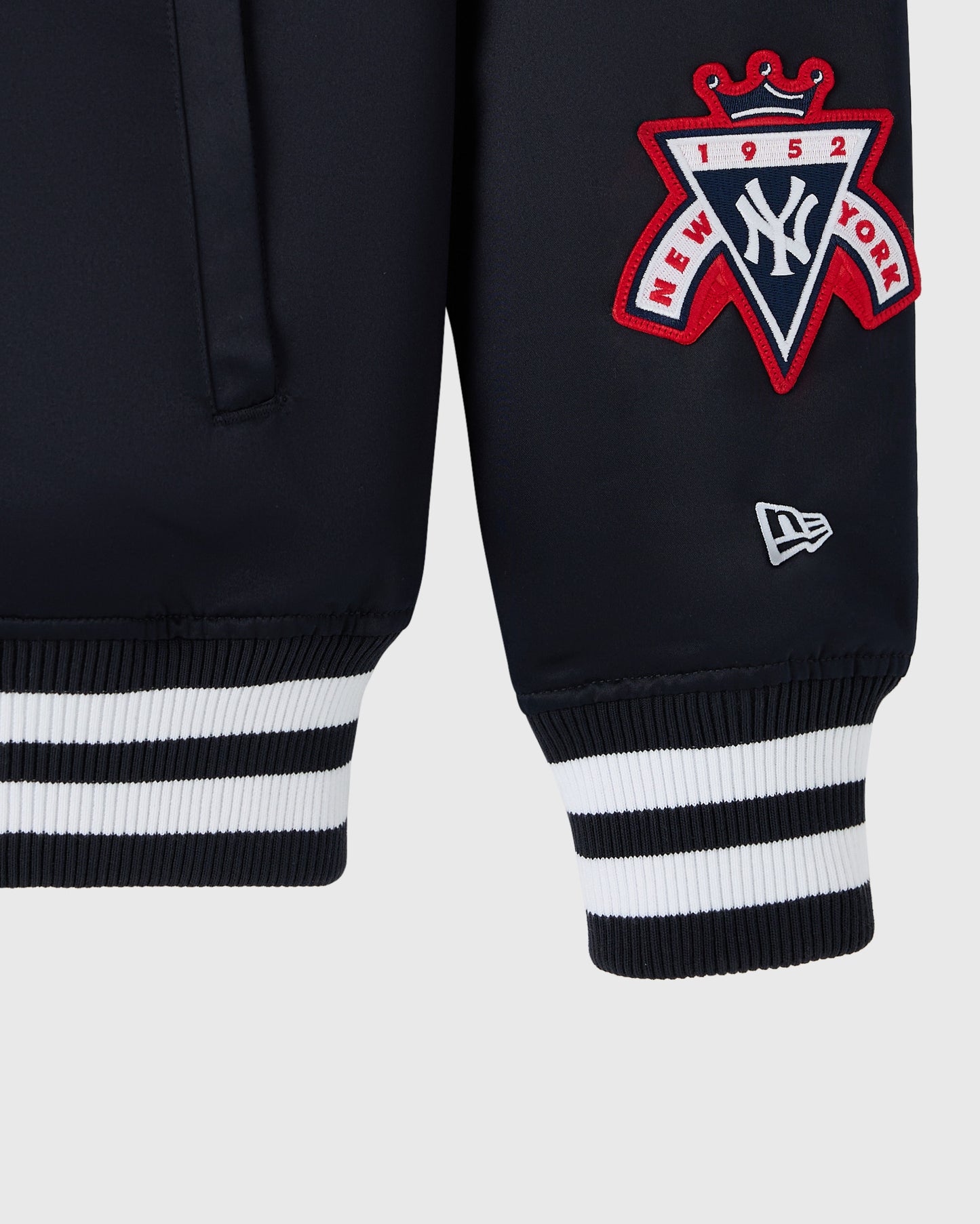 Navy varsity jacket with red and white Yankees crest patch and striped ribbed cuffs.