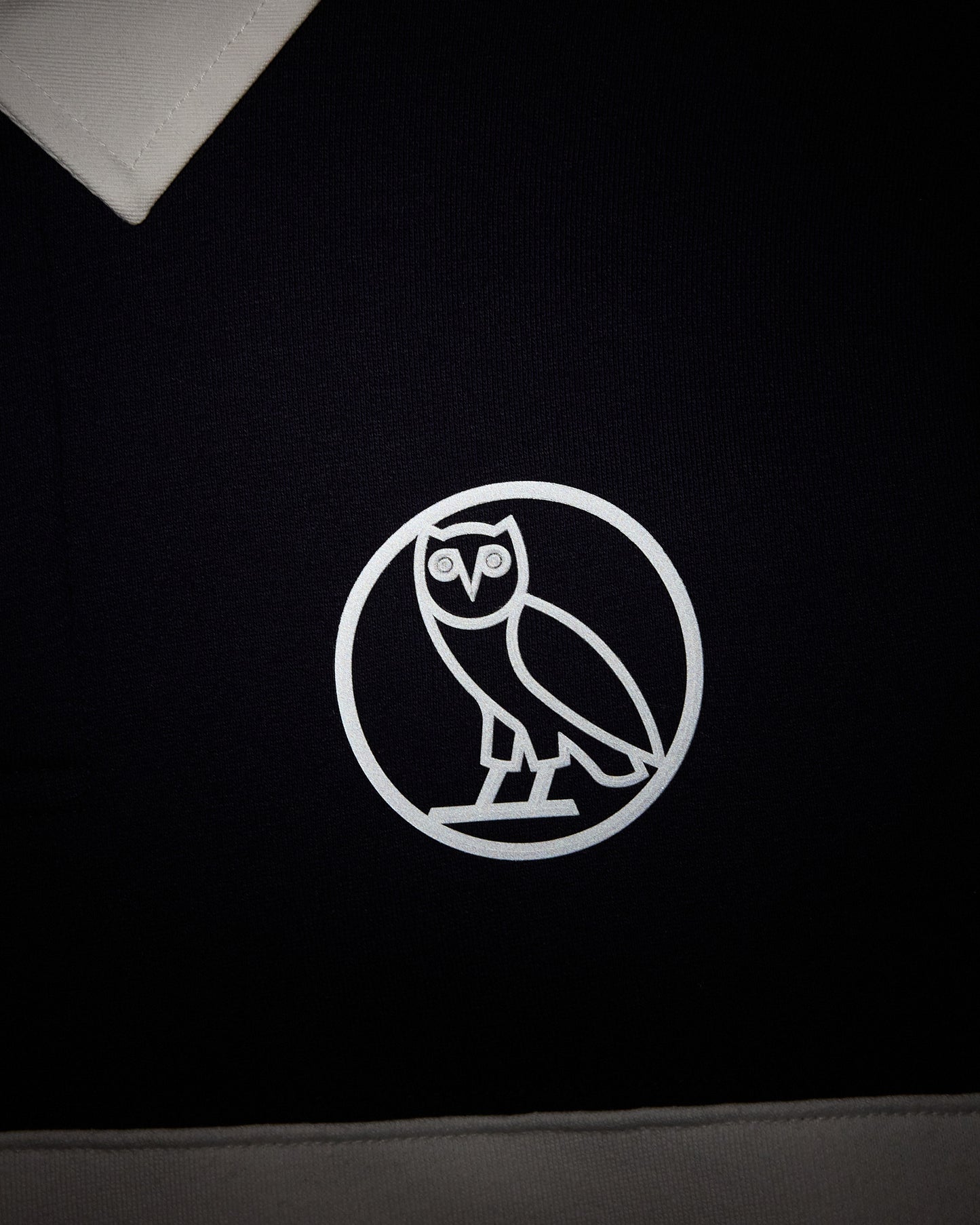 Navy fleece rugby with white owl logo emblem on chest and white collar trim.