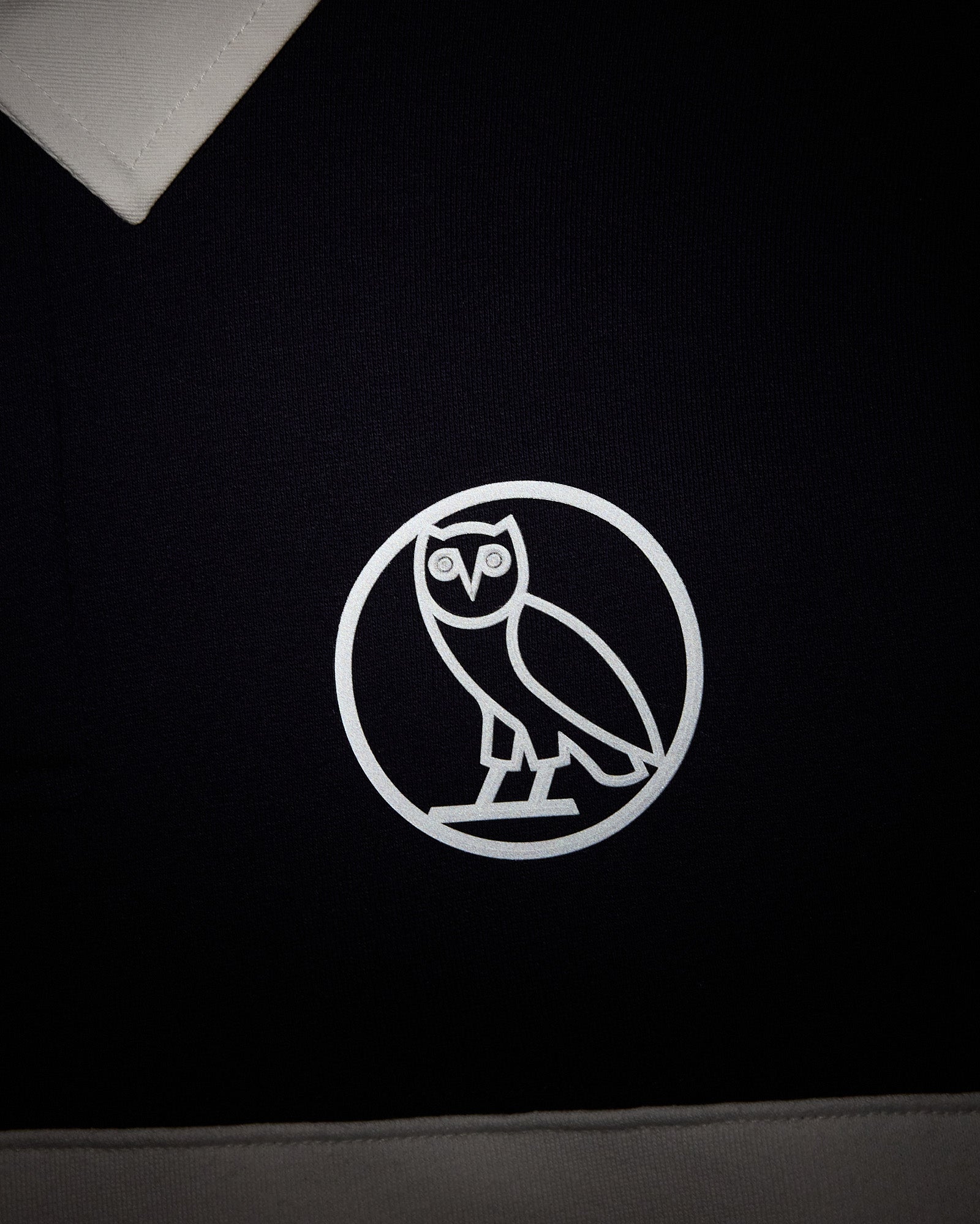 Navy fleece rugby with white owl logo emblem on chest and white collar trim.