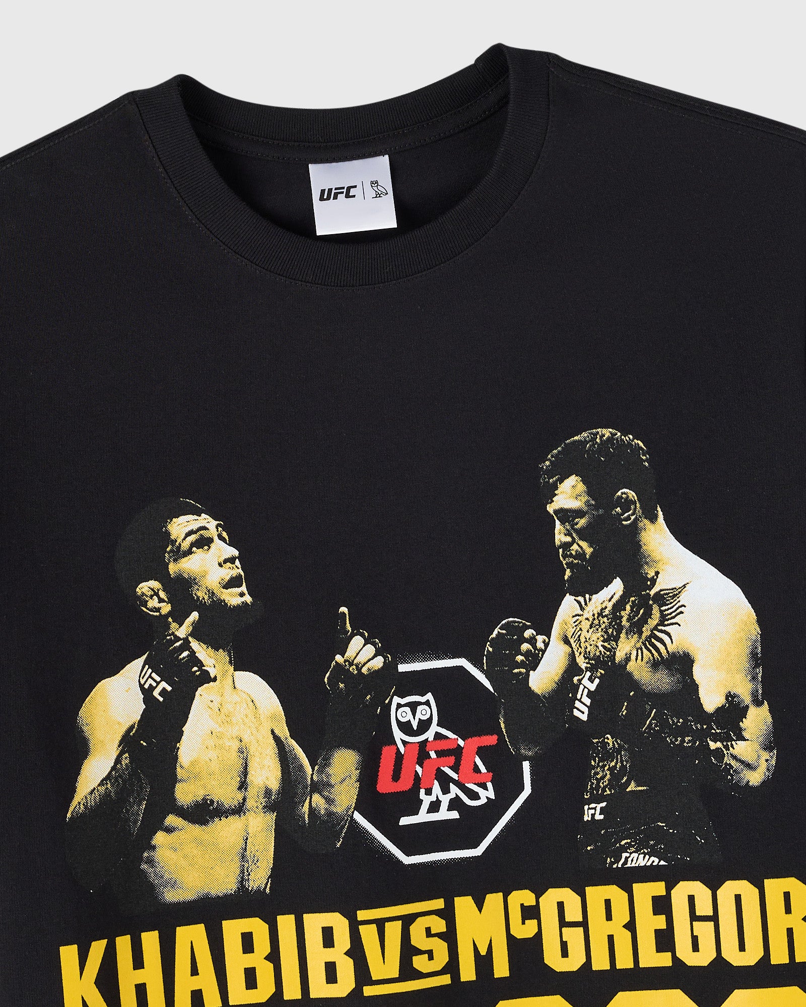 Black t-shirt with UFC logo and gold-toned graphic of two fighters with "KHABIB VS MCGREGOR" text at bottom.