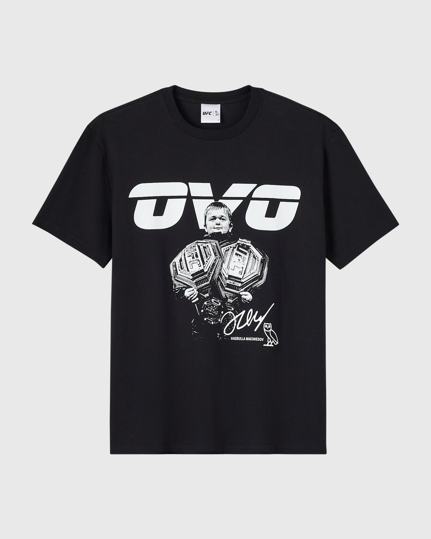 Black t-shirt with white UFC logo and illustration of a Hasbulla holding two championship belts with signature text.
