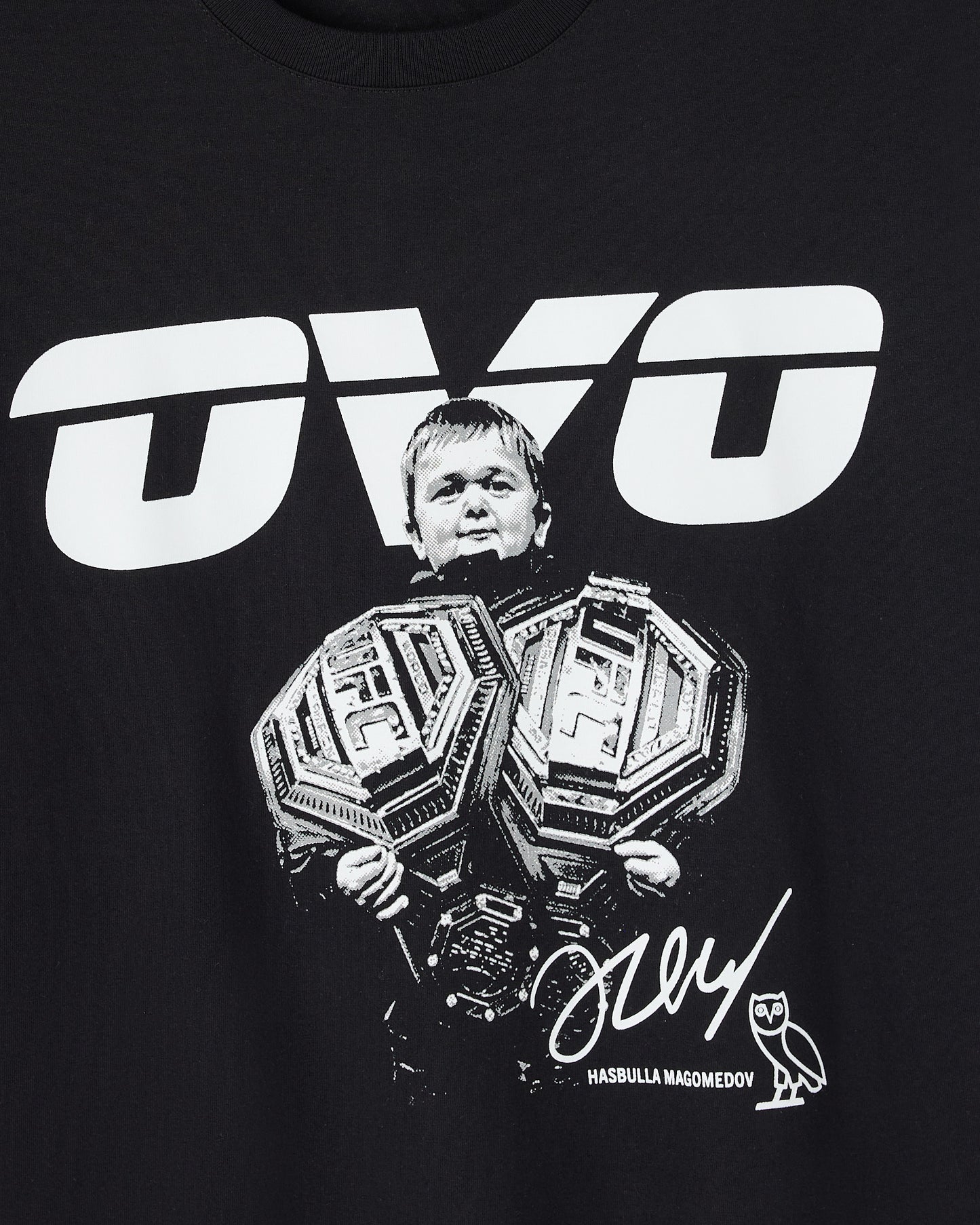 Black t-shirt with white UFC logo and portrait graphic of Hasbulla holding championship belts, signature and name text below.
