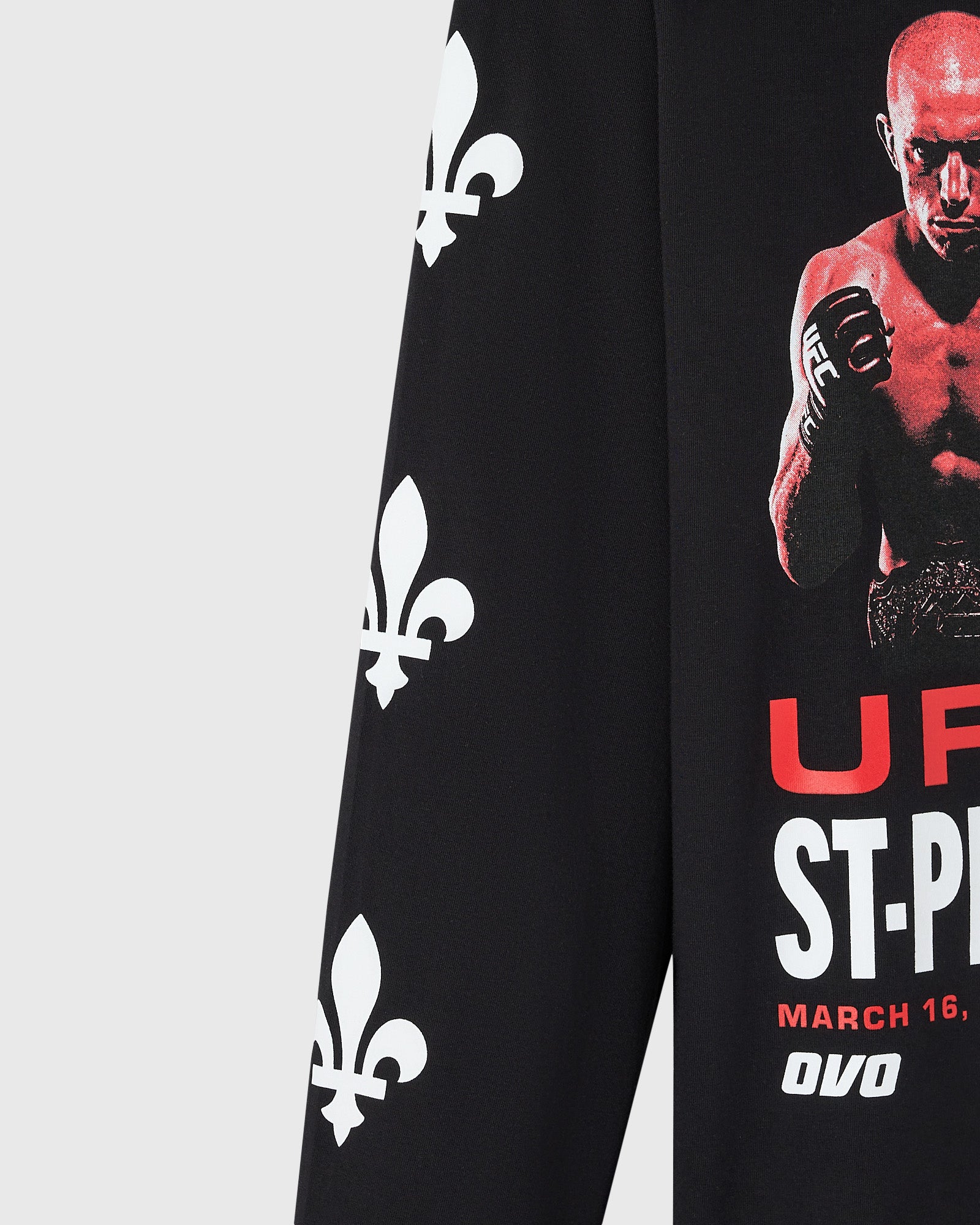 Close up of black long-sleeve tee with white fleur-de-lis pattern on left side and fighter photo with red text