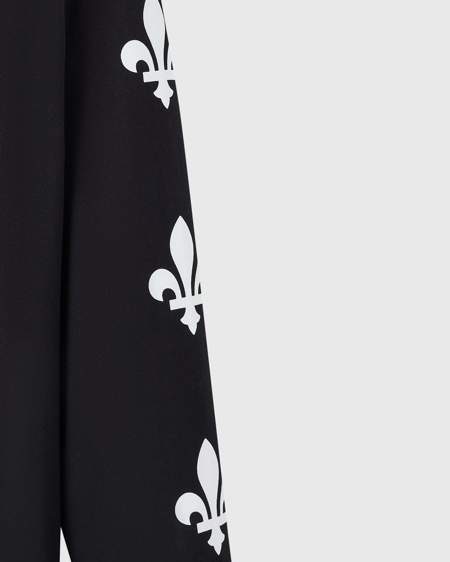 Close up of black long-sleeve tee with white fleur-de-lis symbols printed vertically down the front.