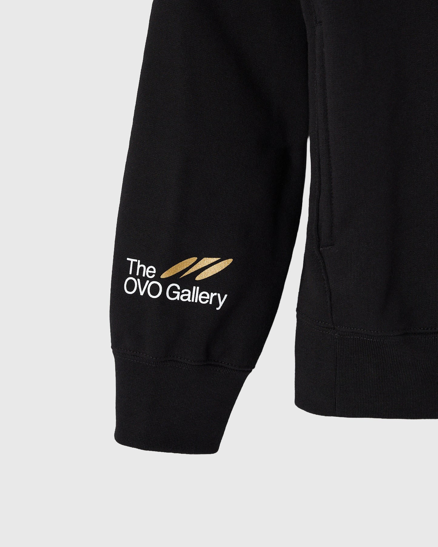 Black hoodie with "The OVO Gallery" logo and gold feather graphic printed on left sleeve.