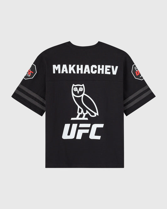 Black short-sleeve tee with white "MAKHACHEV" text, owl graphic, and UFC logo on back; striped sleeves with side patches.