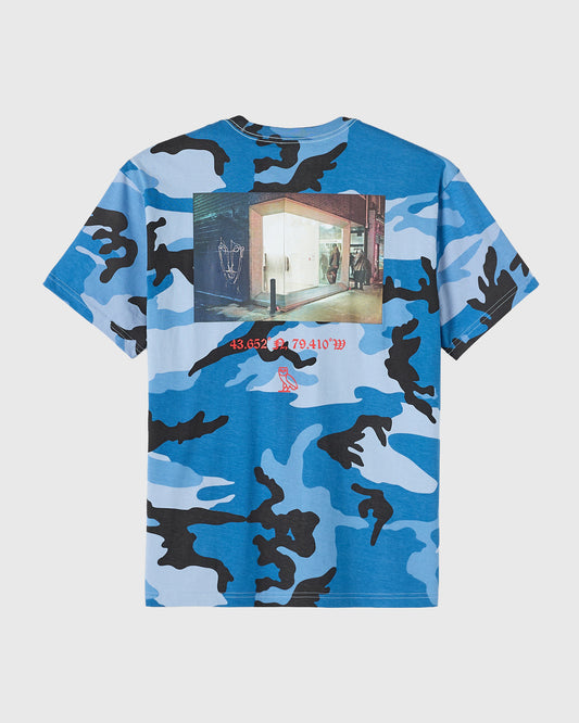 Blue camouflage t-shirt with storefront photograph and coordinate text printed on chest.