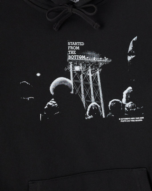 Black hoodie with drawstring and white graphic print featuring "Started From The Bottom" text with industrial tower and figur