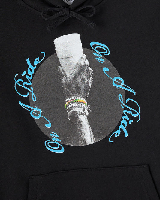 Black hoodie with drawstring, featuring grayscale hand graphic in circular design with blue text and beaded bracelets.